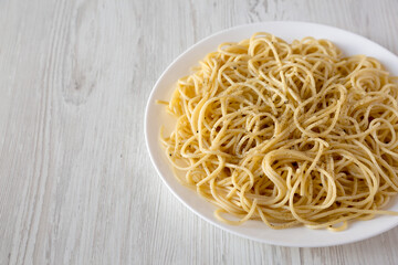 Homemade Cacio E Pepe Pasta with Pecorino Romano and Pepper on a white plate, side view. Copy space.