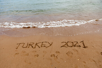 Turkey 2021. The inscription on the sand of the Turkish beach next to the waves of the sea. Holidays in Turkey in 2021.