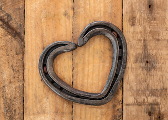 Romantic love heart shaped horse shoe created by farrier laid on rustic vintage wooden plank...