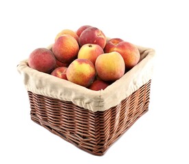 Peaches in a square wicker basket with beige cloth cover. White background.