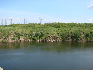 The combination of the natural picture of the rocky banks of the Dnieper on the background of a network of numerous power lines above.