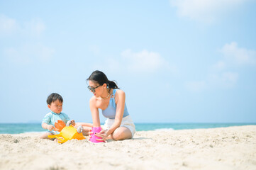 Fototapeta premium Happy family resting at beach in summer, Mother and baby feet at the sea foam at the sunlight water is moving