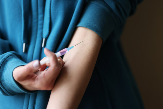 Woman addict injecting drugs into cubital vein closeup