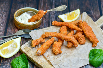 
 Crispy  deep fried home made    chicken strips Breaded  with  almond flour chicken  breast fillets  with chilly peppers and fresh   basil on wooden rustic background. Ketogenic diet food