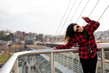 Fototapeta na wymiar Young woman tourist standing with photo camera on the bridge. Beautiful woman traveling around the city