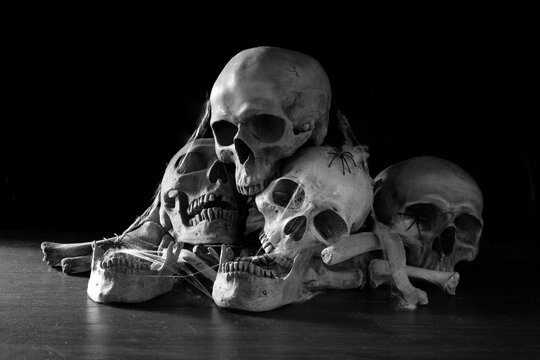 Old skull put on pile of bone on dark ground and black background in morgue,