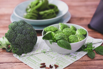 Wooden table with raw broccoli, full and sliced. Vegan or vegetarian concept