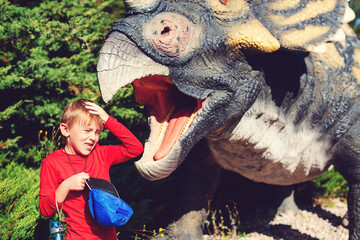 Happy child having fun at dino park. Summer camp, vacation and weekend day.