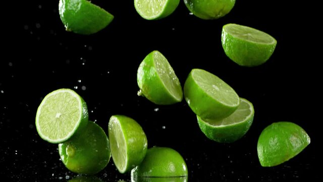 Super slow motion of falling fresh limes, isolated on black background. Filmed on high speed cinematic camera at 1000 fps.