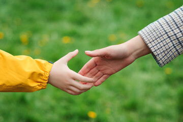 Mother and child hands reaching to each other. Support, help and trust.