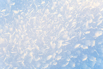 Beautiful gradient, winter natural background of ice and snow crystals illuminated by sun. A closeup of snow crystals. Universal abstract background in white-blue tones for various creative purposes.