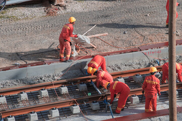 Tel Aviv, Israel - May 20 2021: Construction Workers with Orange overalls. Light rail tracks. blue collar worker. Concept Collaboration teamwork. Trucks, concrete mixer, bulldozer. High quality photo