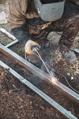 A welder welds metal at a construction site.