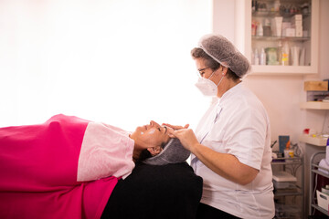 beautician applying facial cream to a lady