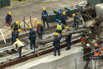 Tel Aviv, Israel - May 20 2021: Construction Workers working in the rain. Light rail tracks. blue collar worker. Concept Collaboration teamwork. Trucks, concrete mixer, bulldozer. High quality photo