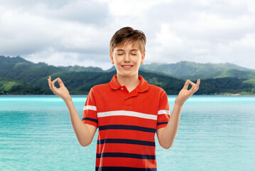 childhood, fashion and people concept - happy smiling boy in red polo t-shirt meditating over hills...