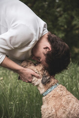 A teenage boy hugs his furry dog on a walk. Irish Soft Coated wheaten terrier.