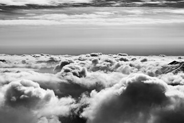 Black and white snowy high mountains covered with beautiful sunlight clouds