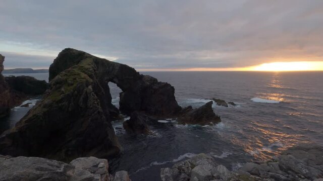 4k time lapse of sunset at Stac a Phris sea arch, Isle of Lewis, Outer Hebrides, Scotland. Calm sea, sun on horizon lighting up arch and sea.