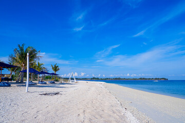 Tropical sea with white sand beaches, blue sea, blue sky, green trees and sun lounge. Gili Trawangan, Indonesia