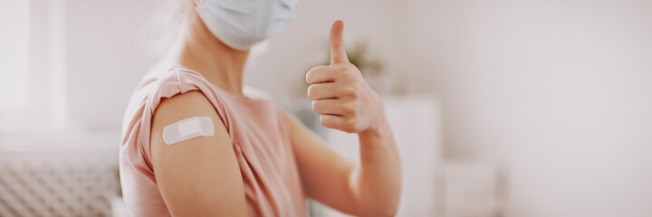 Woman showing thumb up after inoculation against Covid 19. - obrazy, fototapety, plakaty