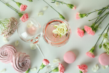 Wine, sweet food and flowers on white table