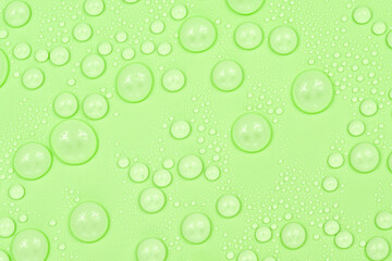 Water drops on green background texture. Backdrop glass covered with drops of water. green bubbles in water.