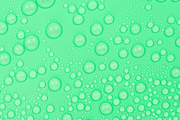 Water drops on green background texture. Backdrop glass covered with drops of water. green bubbles in water.