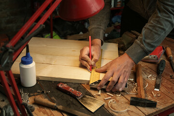 Carpenter measuring and marking wood with speed square measure tool in workshop	