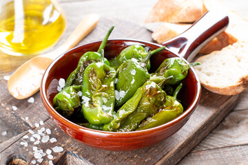 Authentic Spanish padron peppers with salt and olive oil on frying pan on a table