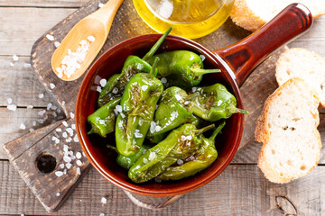 Green pepper Padron baked or fried in the Spanish style in a frying pan on a table. Top view