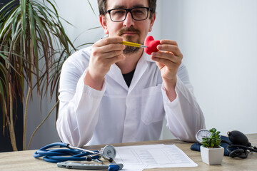 Doctor at workplace in office during appointment looks into camera, shows patient anatomic model of urine bladder with focus on hand with organ. Professional medical diagnosis diseases of urinary