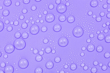 Water drops on purple background texture. Backdrop glass covered with drops of water.  violet bubbles in water