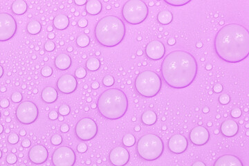 Water drops on purple background texture. Backdrop glass covered with drops of water.  violet bubbles in water