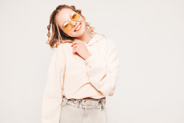 Young beautiful woman looking at camera.Trendy female smiling in casual summer clothes. Positive and funny model posing on grey background in studio in sunglasses