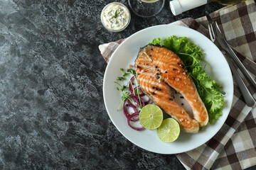 Concept of tasty eating with grilled salmon on black smokey table