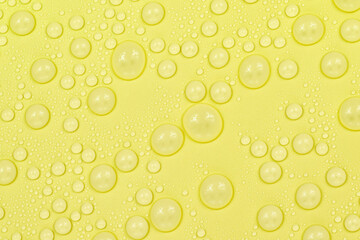 Water drops on yellow background texture. Backdrop glass covered with drops of water. yellow bubbles in water. beer texture
