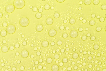 Water drops on yellow background texture. Backdrop glass covered with drops of water. yellow bubbles in water. beer texture