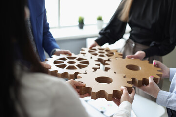 Efficient business team connects wooden gears into one