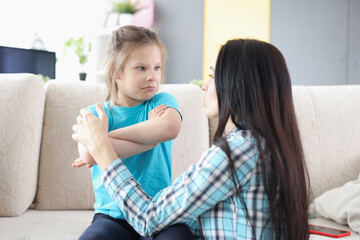 Sad offended daughter sitting on couch, turning back to mother after quarrel at home