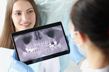Dentist doctor examines x-ray of female patient jaw