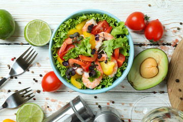Concept of tasty eating with shrimp salad on white wooden table