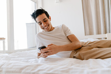 Smiling young hispanic man using mobile phone