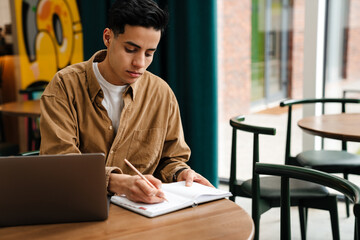 Obraz premium Young hispanic man student sitting at the cafe table indoors