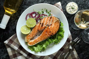 Concept of tasty eating with grilled salmon on black smokey table