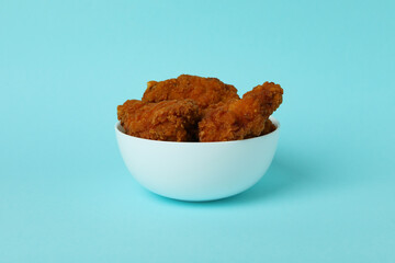 Plate with fried chicken on blue background