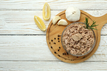 Bowl with canned tuna on white wooden background
