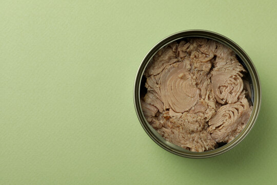 Tin with canned tuna on green background