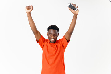 smiling man with a phone in his hands holds his hands above his head light background