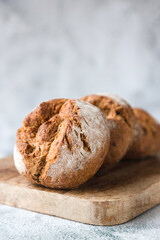 Round fresh buns made from whole grain or rye flour lie on a wooden board. Traditional baked goods in Europe. Place for your text. Bakery, production of bakery products